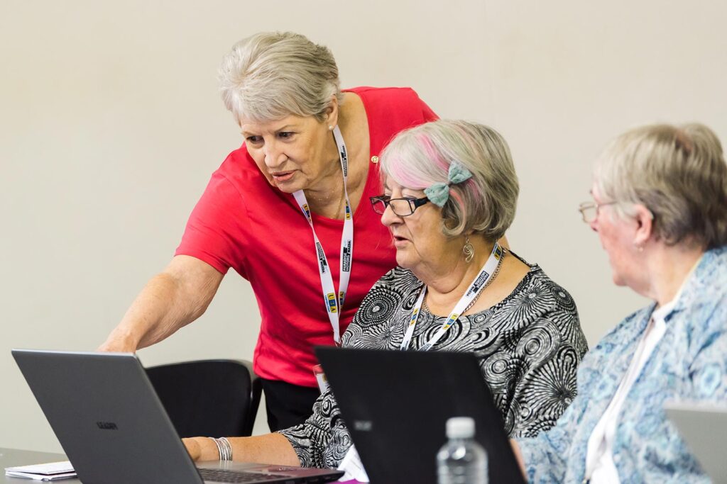 Women helping each other use a laptop